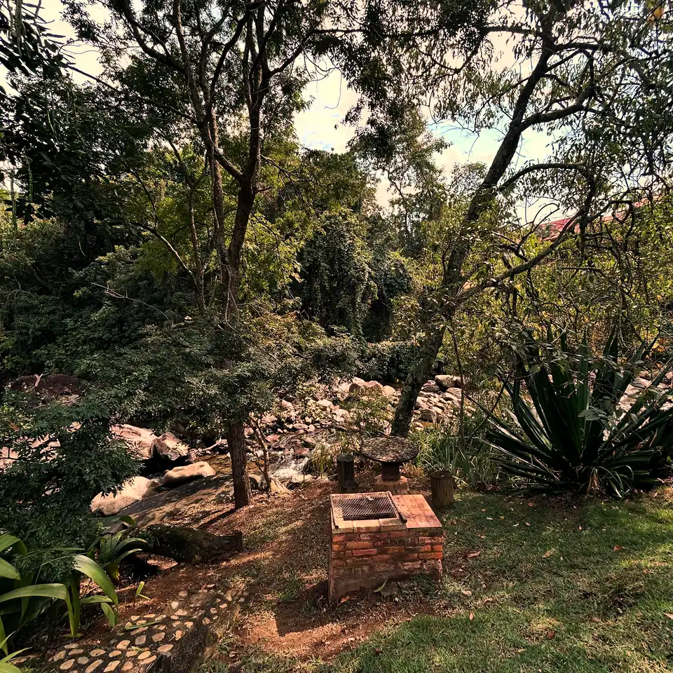 Churrasqueira de tijolo à beira do rio, entre árvores e pedras