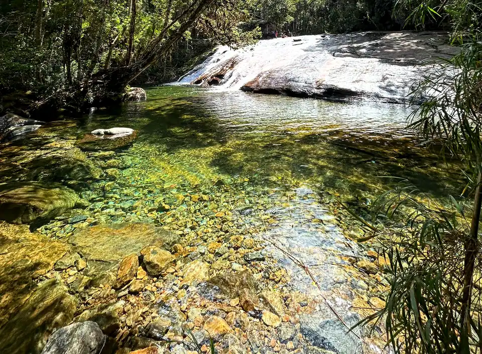Poço de água verde e cristalina no rio, com a correnteza descendo pela pedra lisa